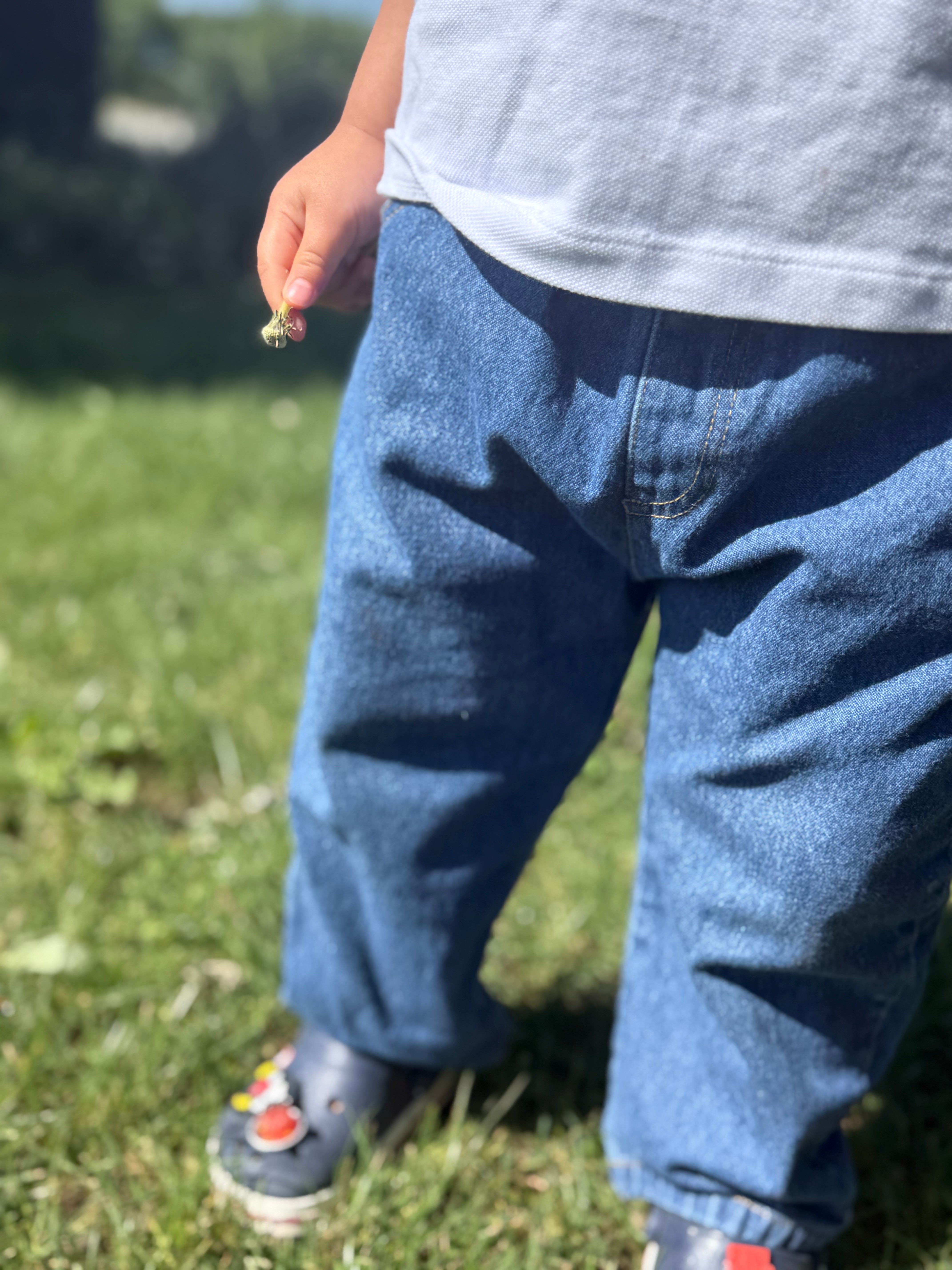 Toddler wearing blue jeans and a white shirt outdoors on grass