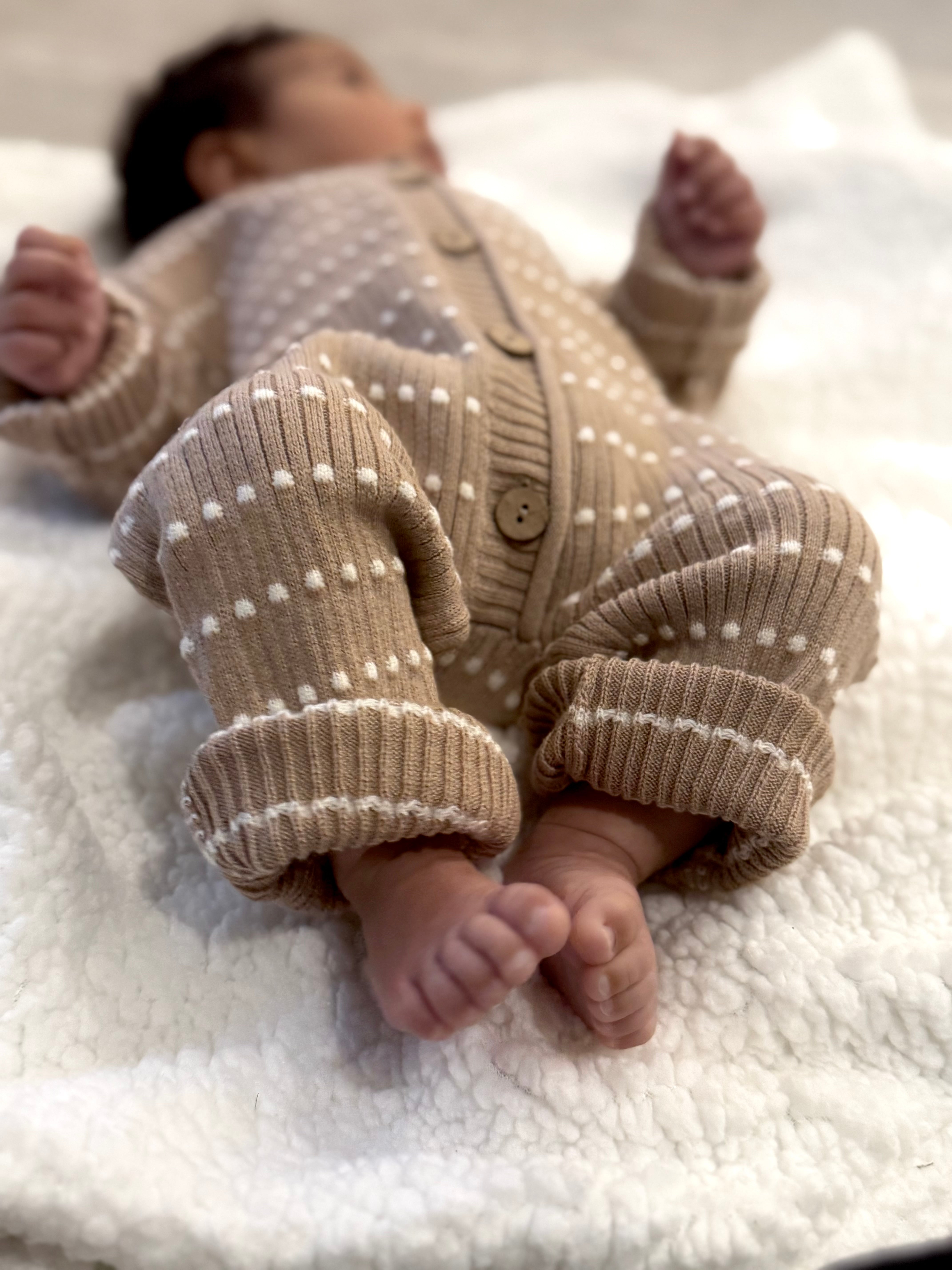Close-up of an Atelier knit romper with rolled cuffs