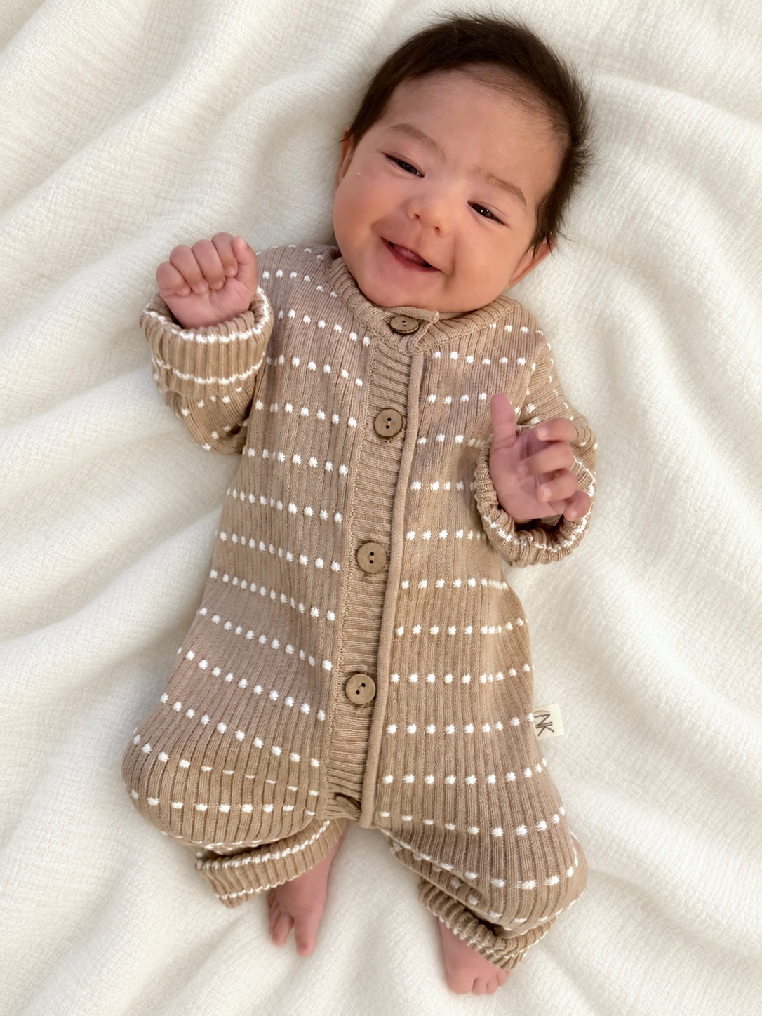 Smiling baby wearing an Atelier knit romper