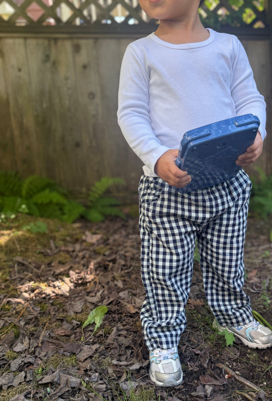 Child holding a blue toy in a garden setting