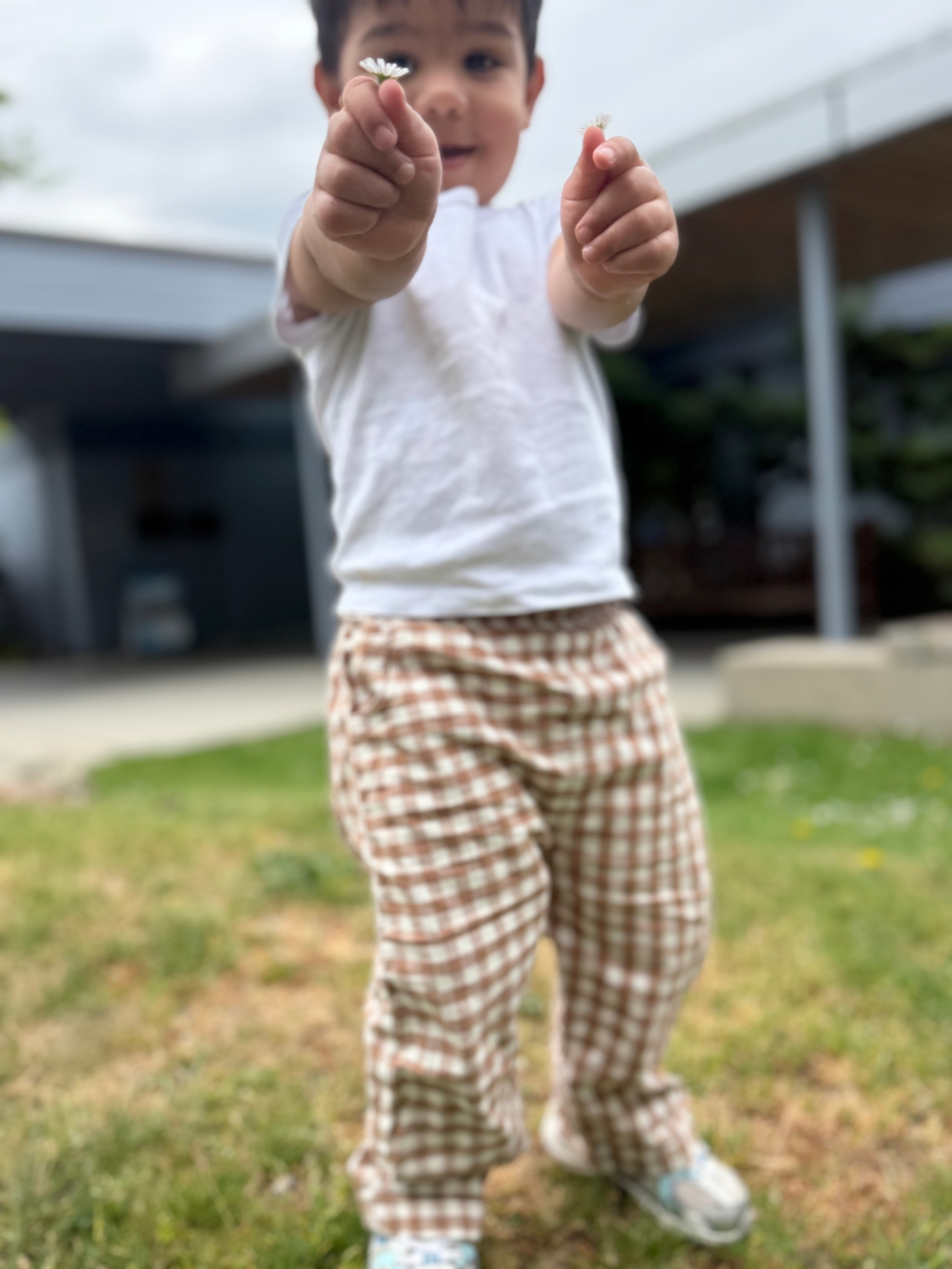Child holding something small between their fingers outdoors