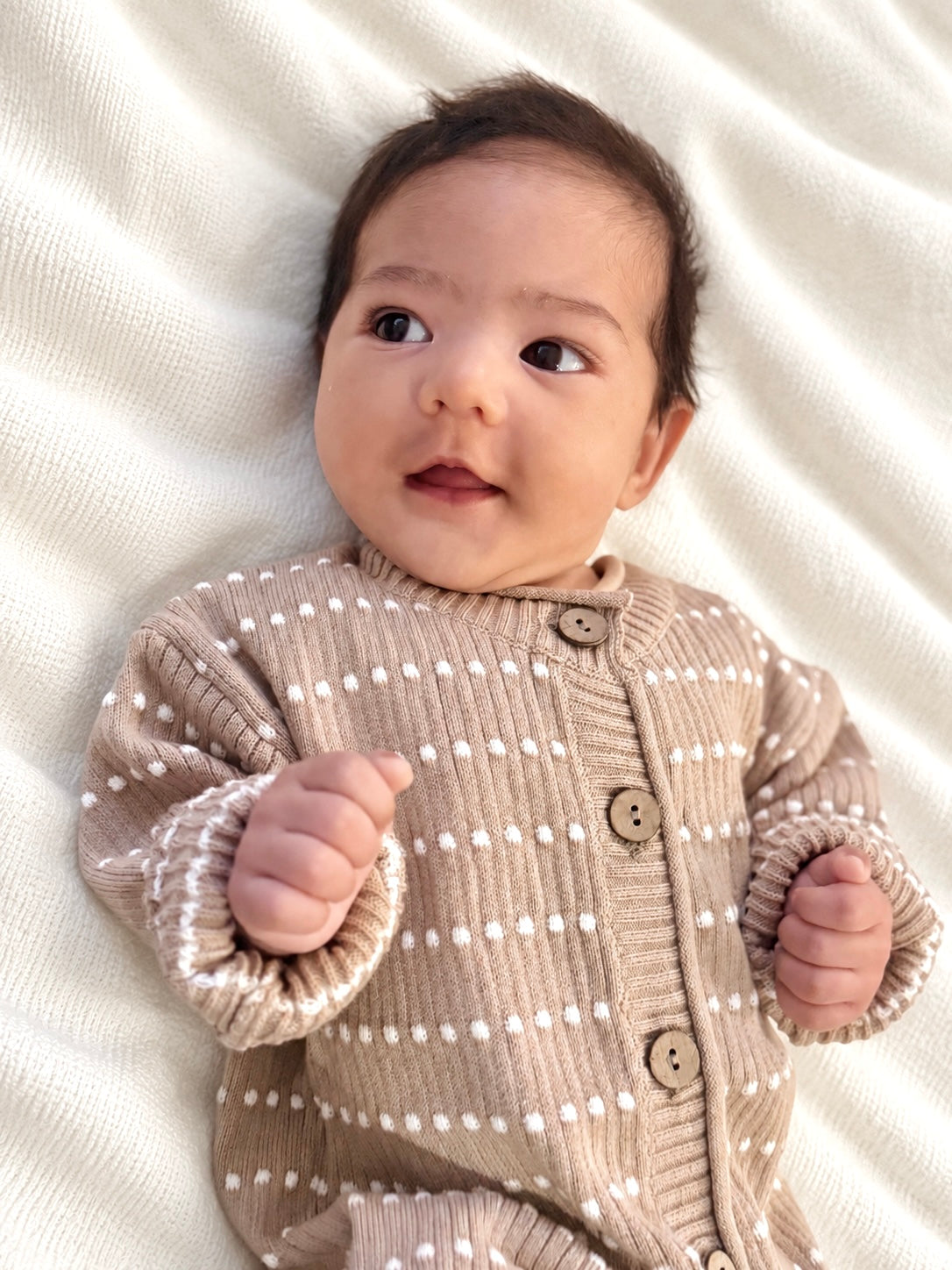 Baby wearing an Atelier knit romper on a cream blanket