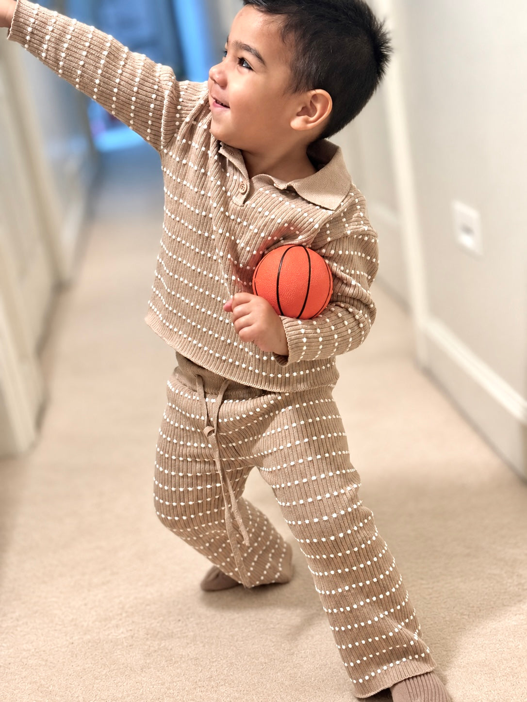 Child playing in a brown-beige Atelier knit outfit
