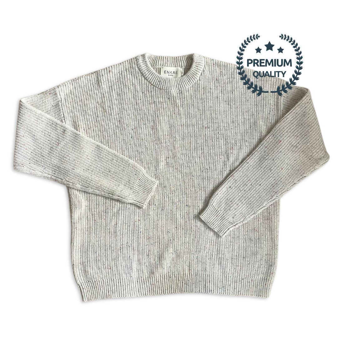 Flat lay of the Matching Mommy and Me Confetti Sweater set. The neutral beige color with colorful specks is showcased on both adult and baby sizes, made from soft, premium cotton. The cozy, playful design is perfect for matching family outfits.