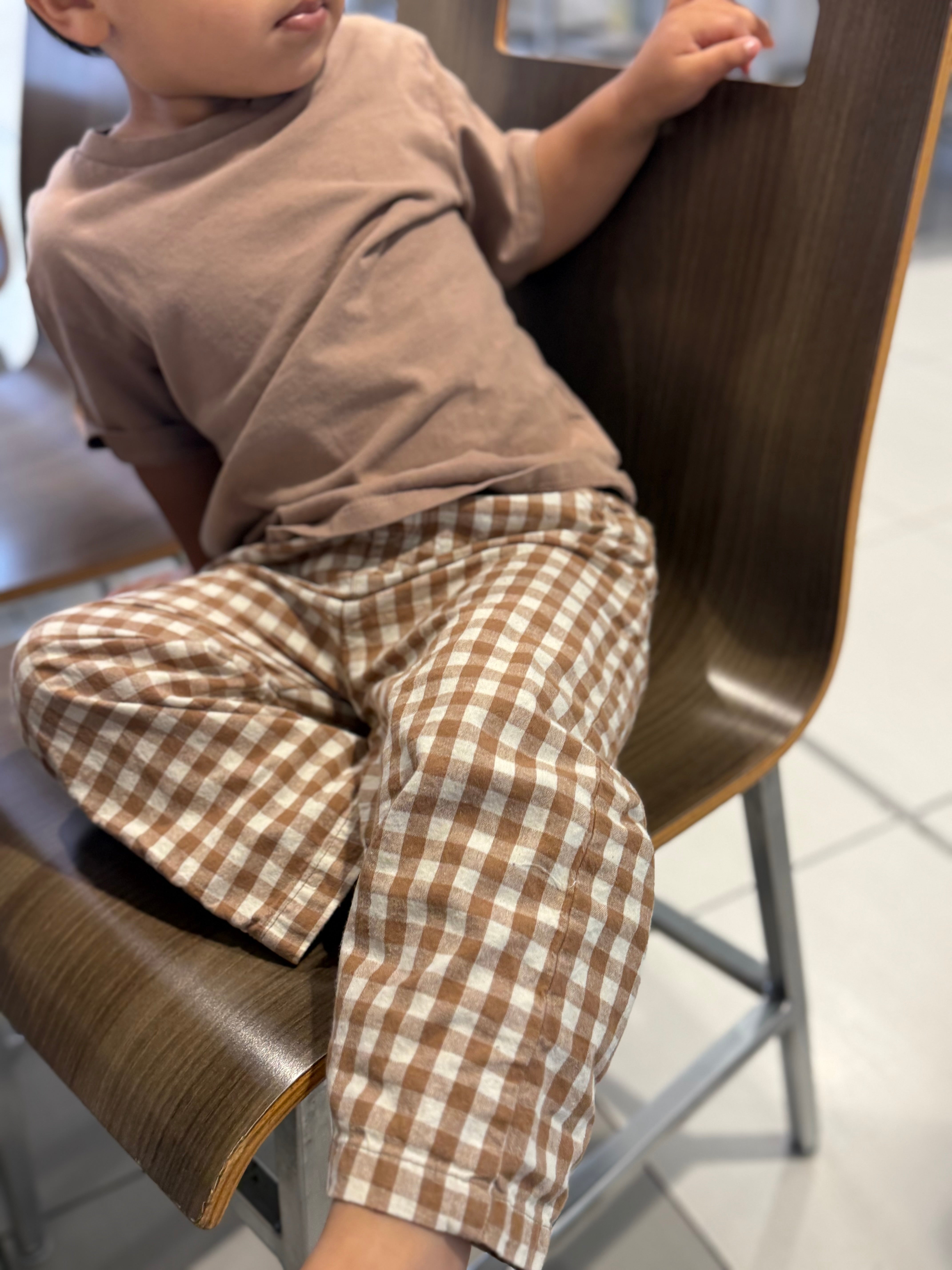 Child sitting on a chair wearing a brown checkered outfit