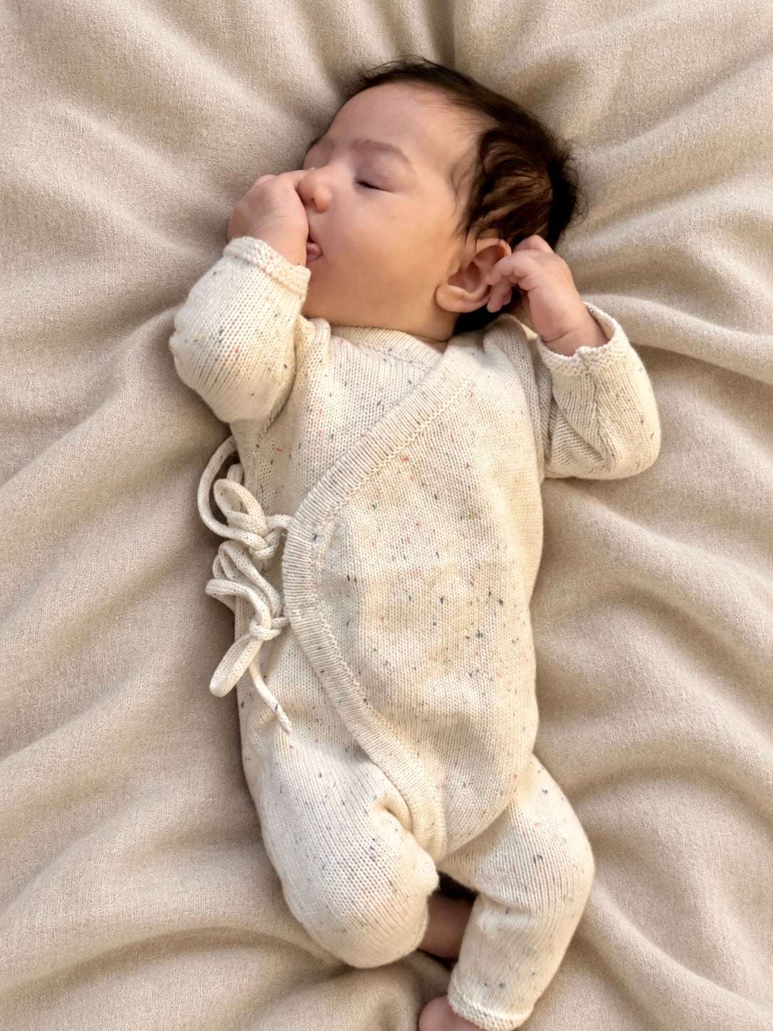 Baby lying on a blanket in a cream Confetti Tie Romper