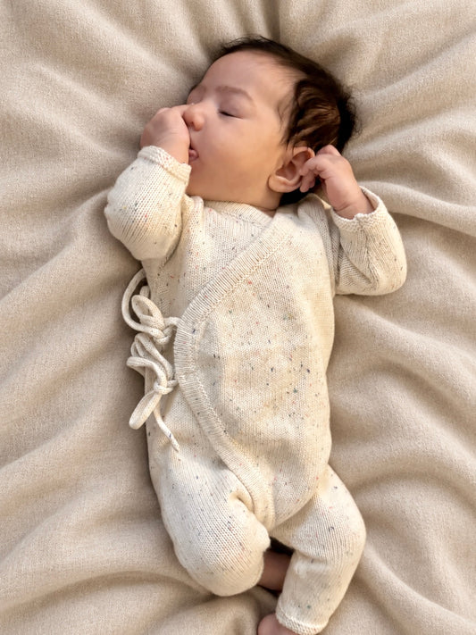Baby lying on a blanket in a cream Confetti Tie Romper
