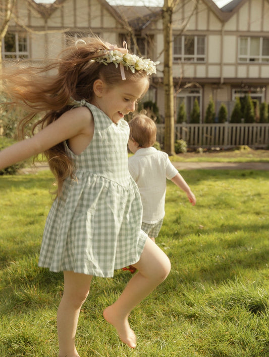 Two children running in a grassy yard with a house in the background