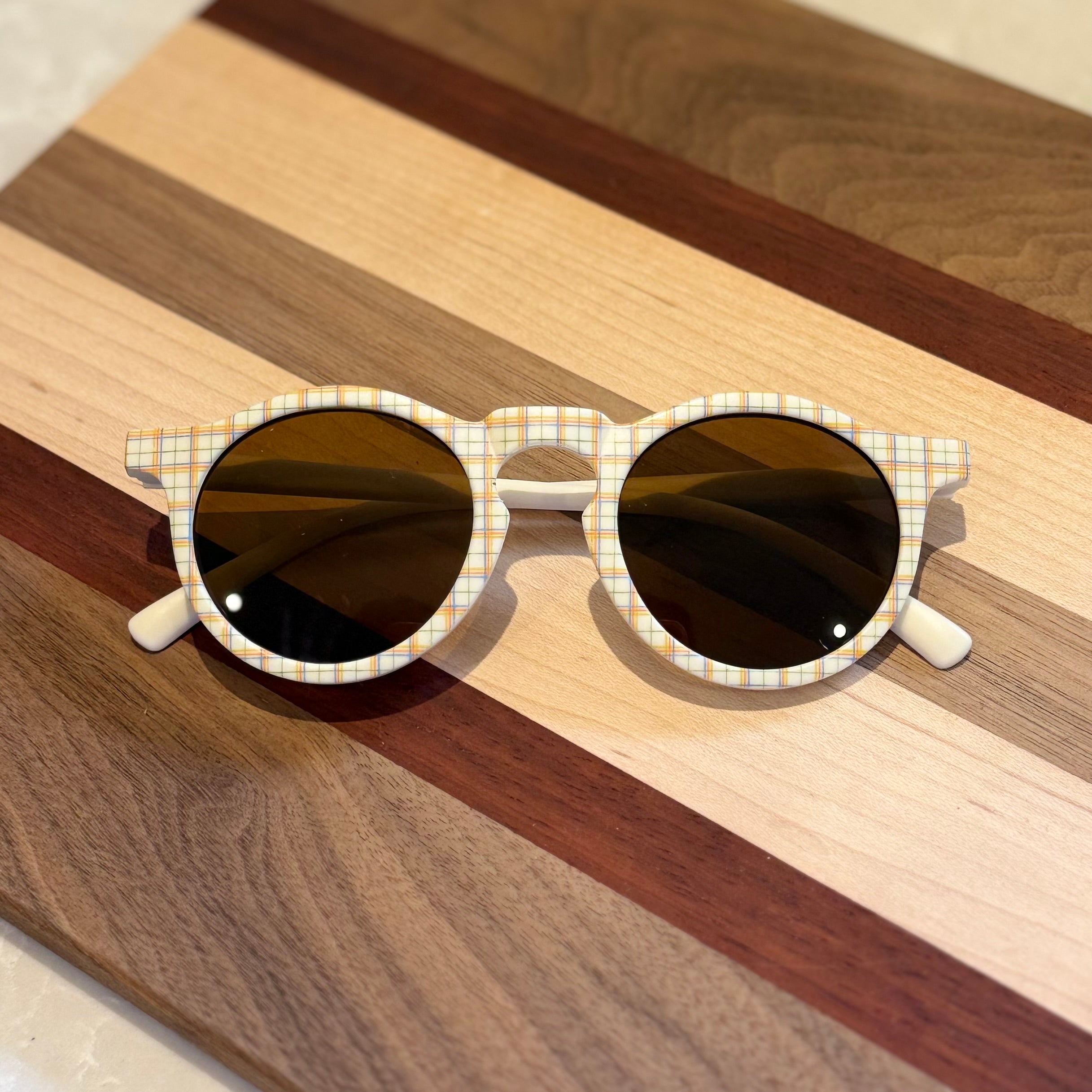 Sunglasses with plaid frame on a wooden surface