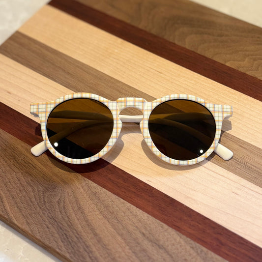 Sunglasses with plaid frame on a wooden surface